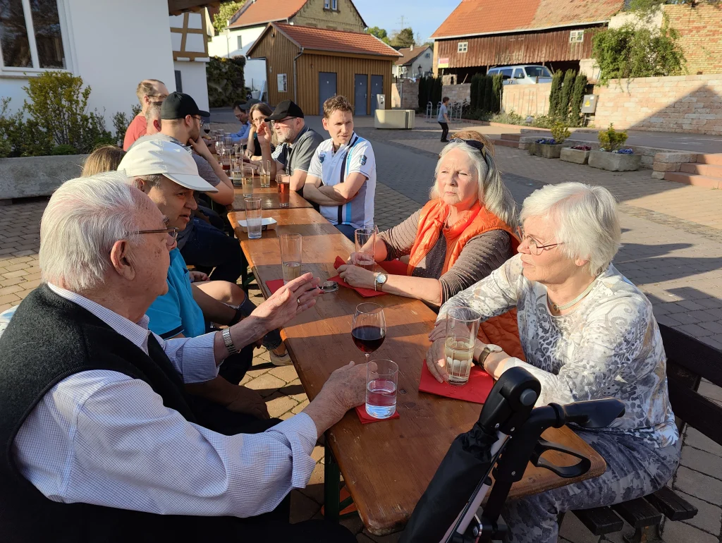 Menschen sitzen sich gesellig an einem Tisch gegenüber und unterhalten sich bei einem Glas Wein.